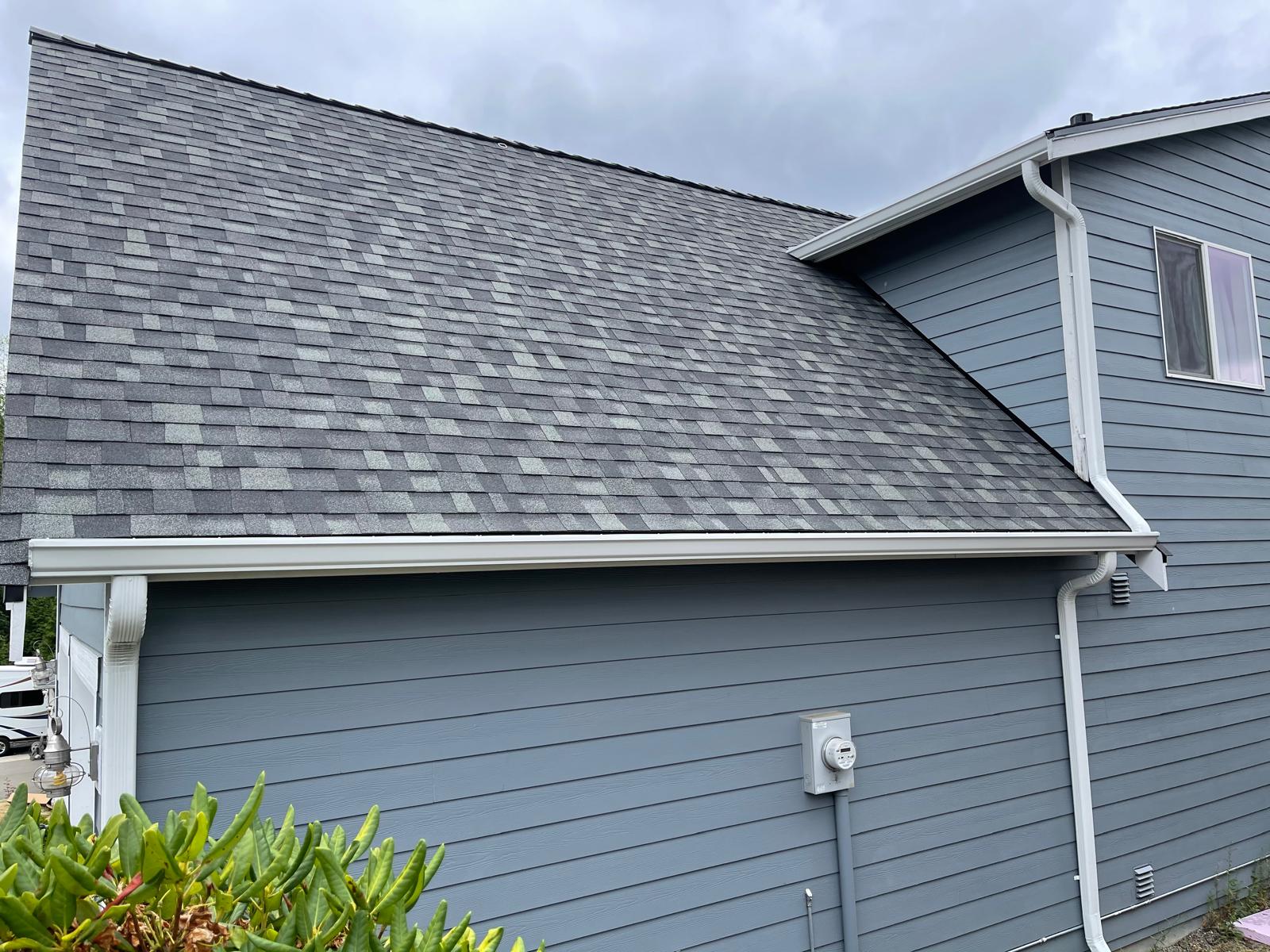 Grey shingle roof and new white seamless gutters and downspout on a home in the Greater Eastside, WA