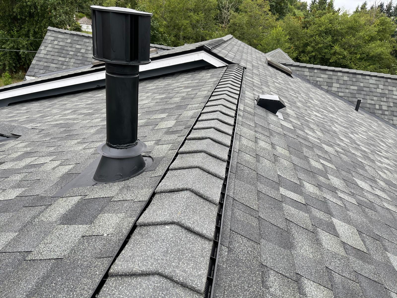 Ridge vent and pipe boot detail along the ridge of a shingle roof in the Greater Eastside, WA