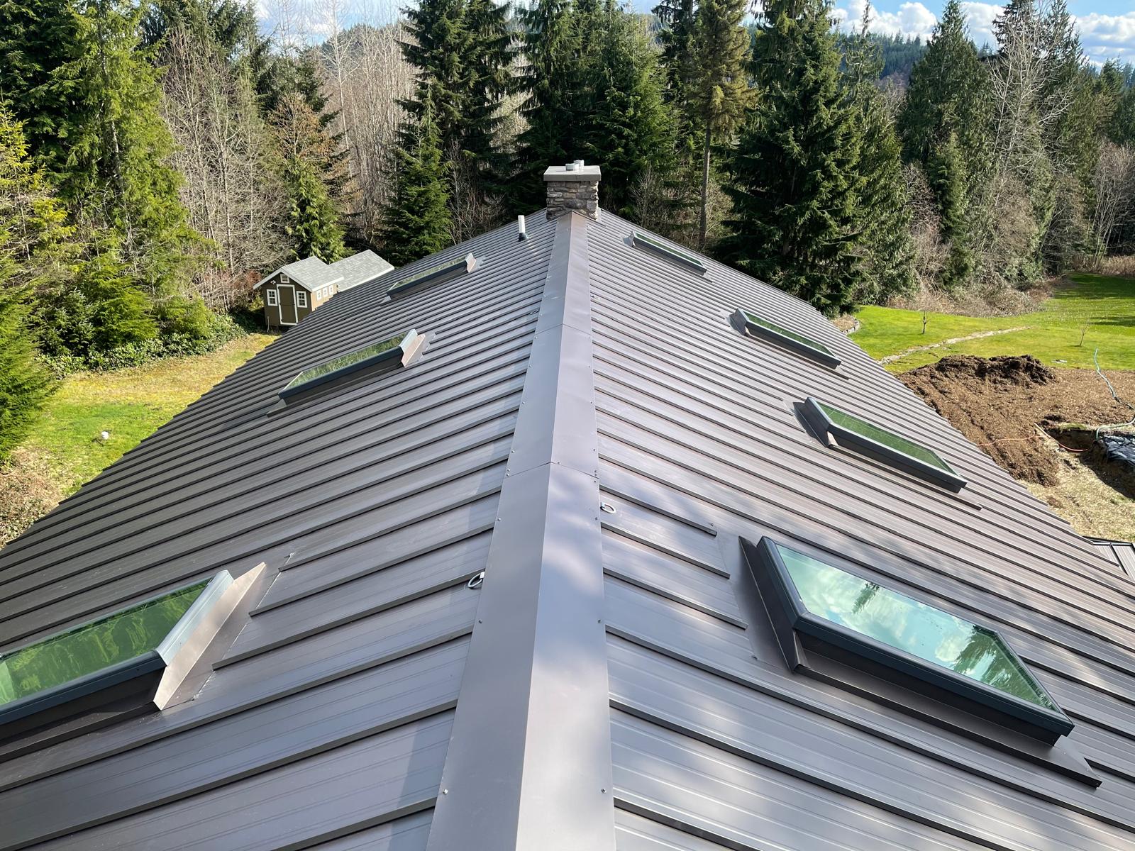 Dark bronze standing seam metal roof with flashed skylights on a home in the Greater Eastside, WA
