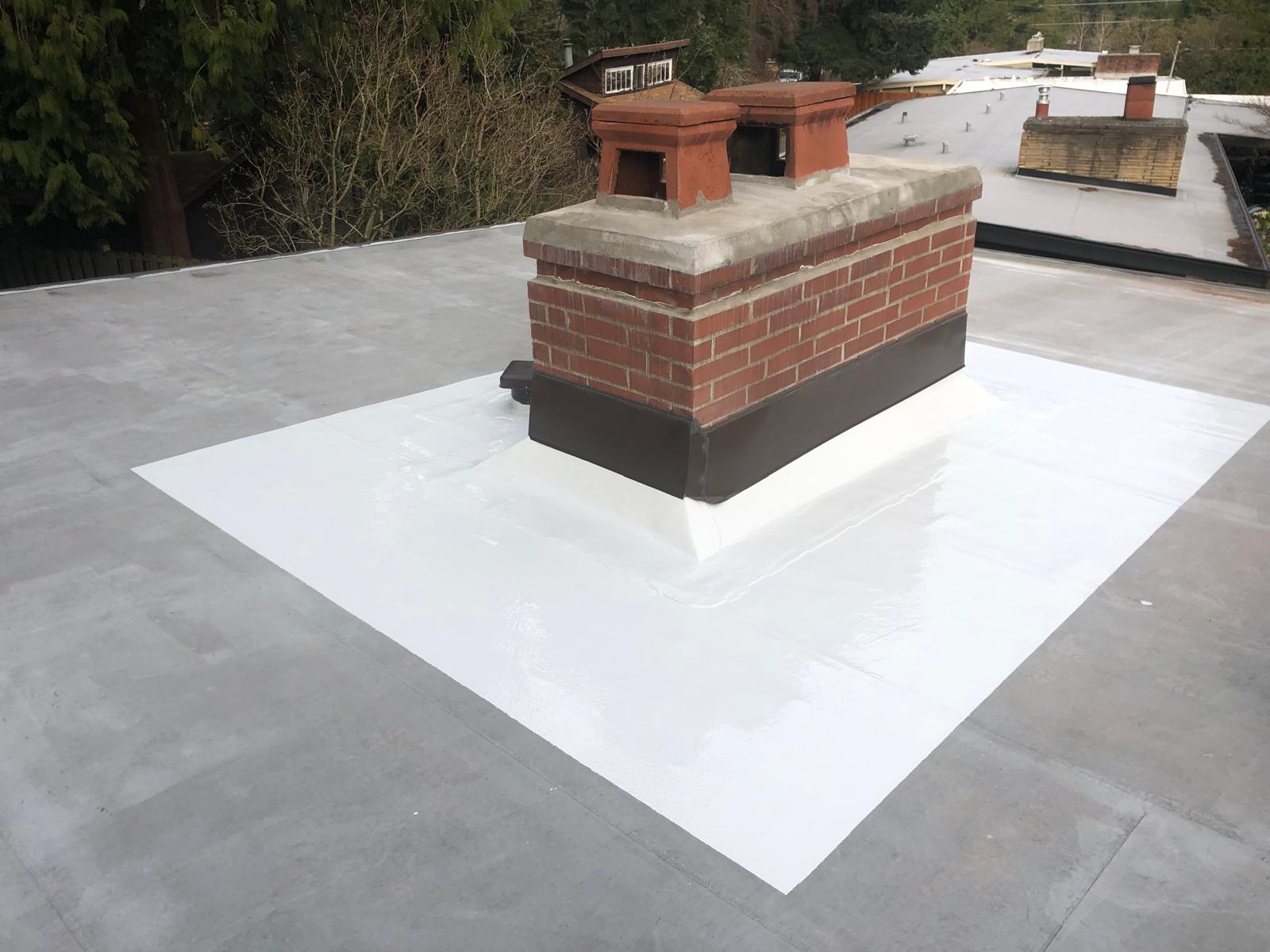 New white PVC membrane flashing around a brick chimney on a flat roof